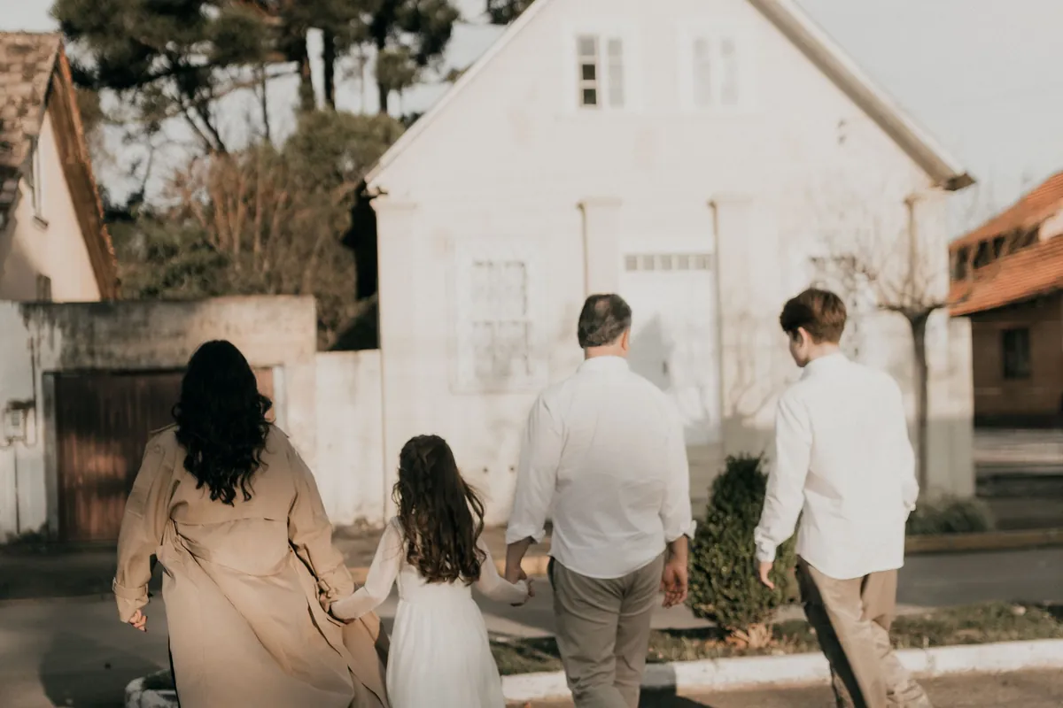 Une famille de quatre, vue de dos, marche vers sa maison
